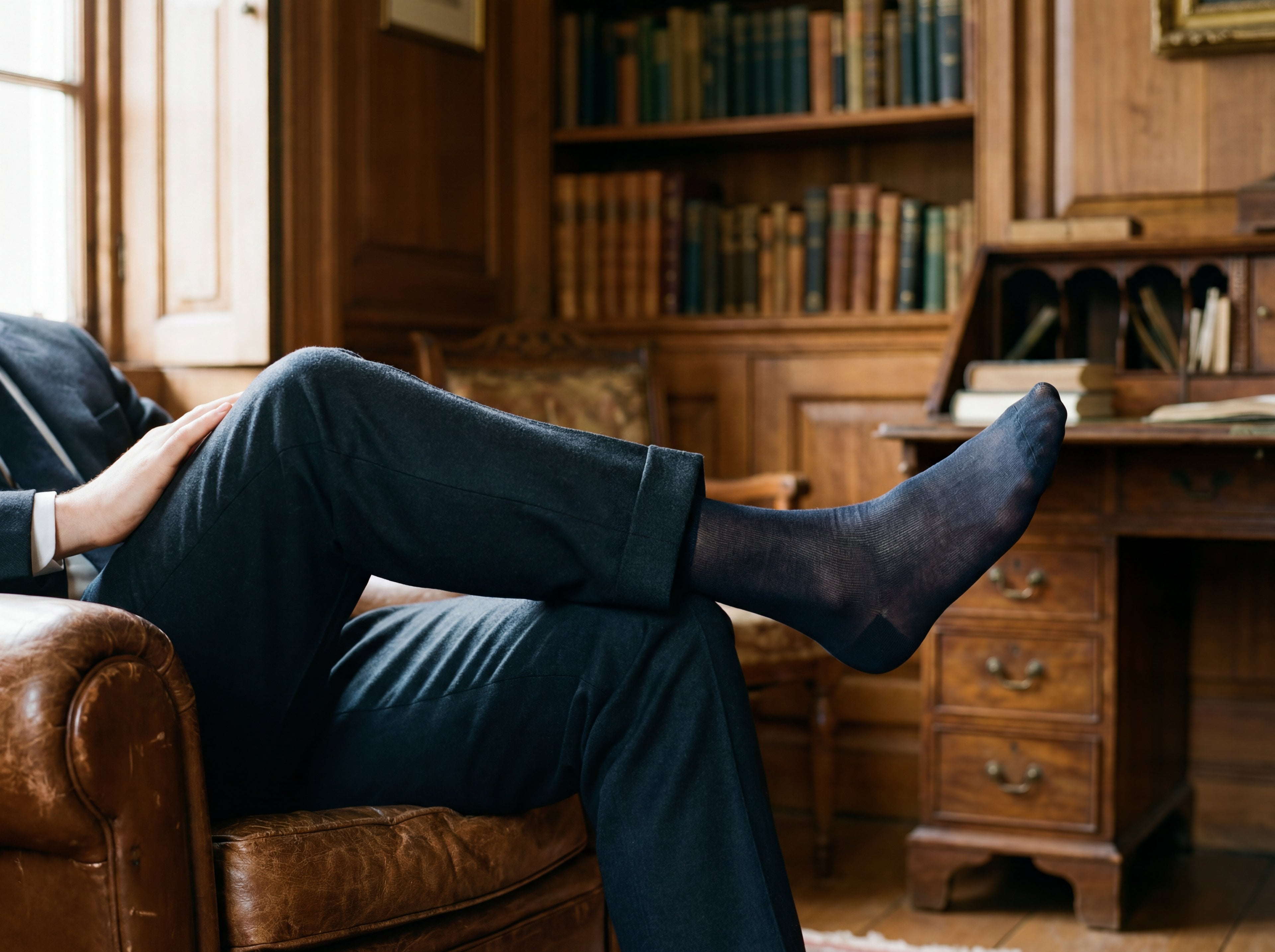 Uomo elegante seduto con calze lunghe sottili e scarpe classiche