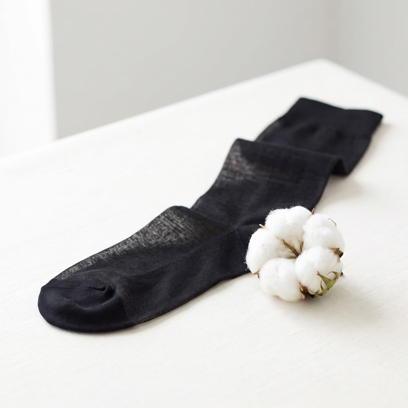 Calza lunga sottile in cotone Filo di Scozia accanto a un batuffolo di cotone
