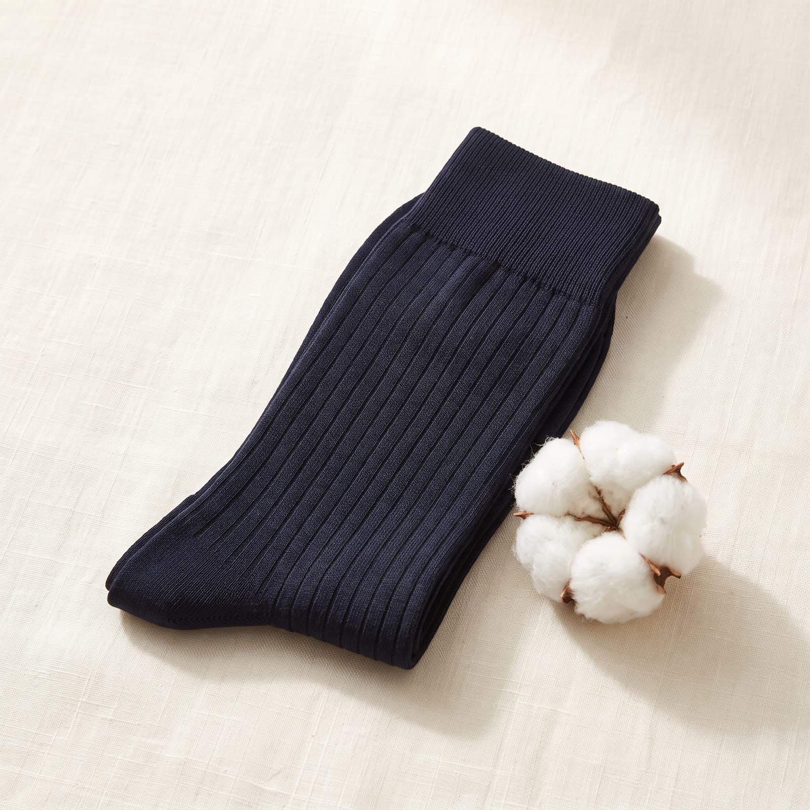 Calze lunghe blu navy in Filo di Scozia ripiegate accanto a un batuffolo di cotone
