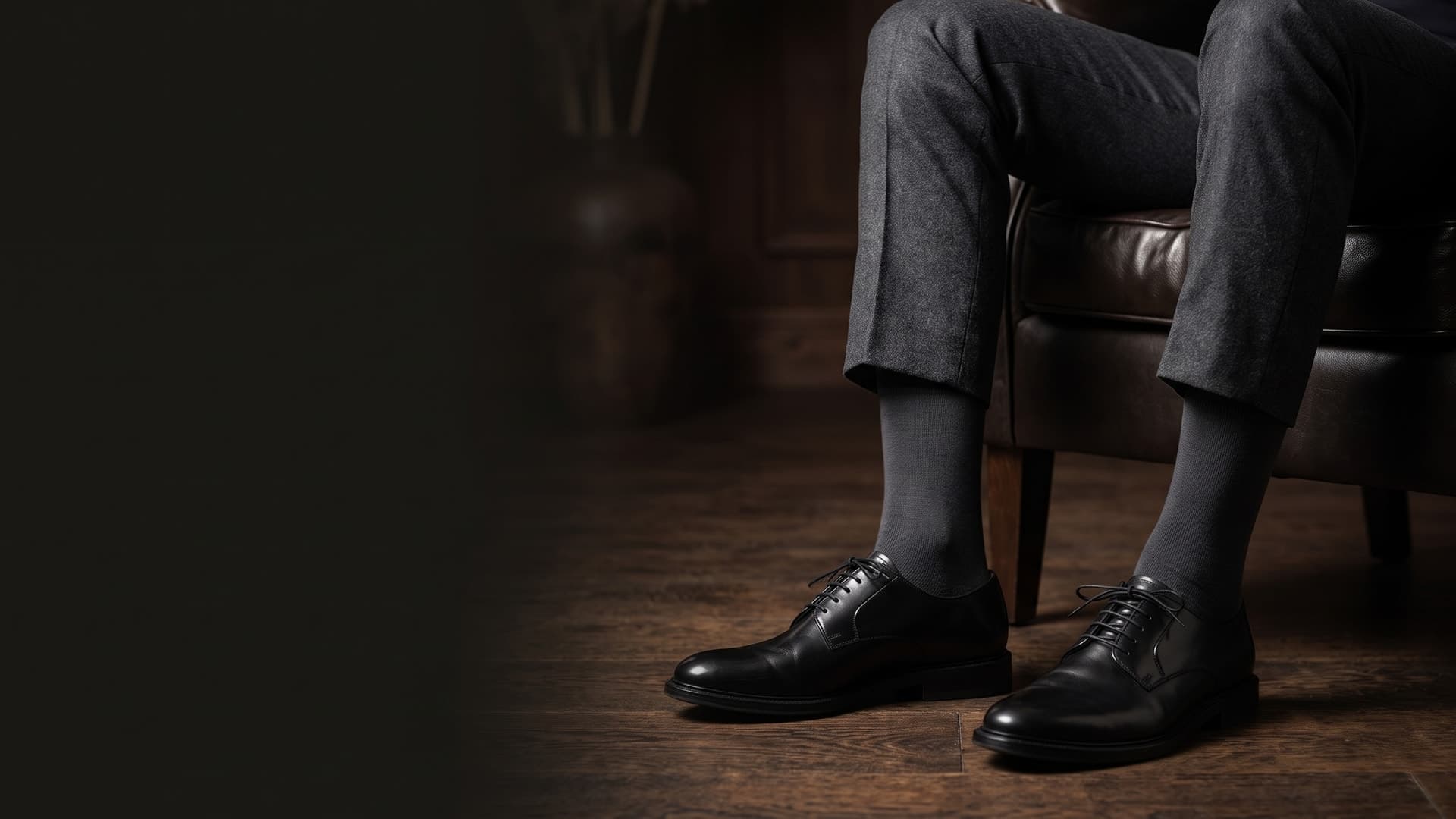 Uomo seduto con pantaloni scuri, calze corte antracite e scarpe nere