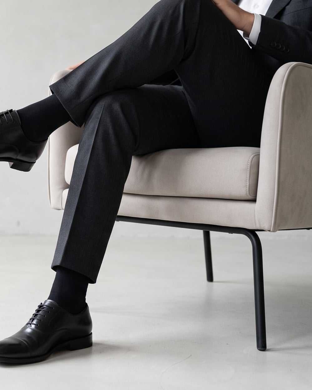 Uomo in abito scuro seduto con calze lunghe nere in cotone sotto i pantaloni