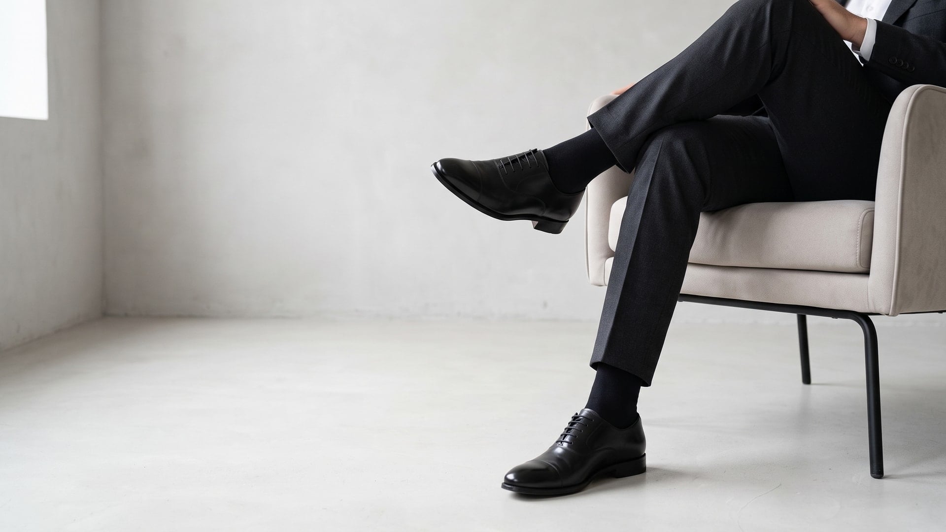 Uomo in abito scuro seduto con calze lunghe nere in cotone sotto i pantaloni