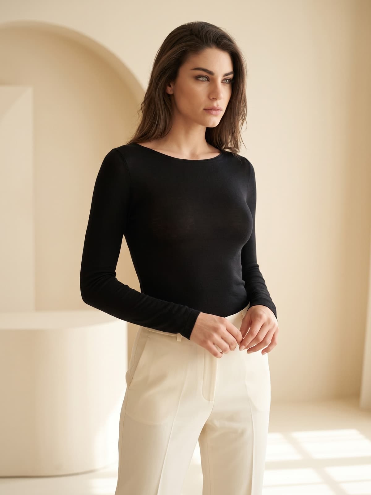 Donna con maglia intima nera a manica lunga e scollo a barchetta, pantaloni panna