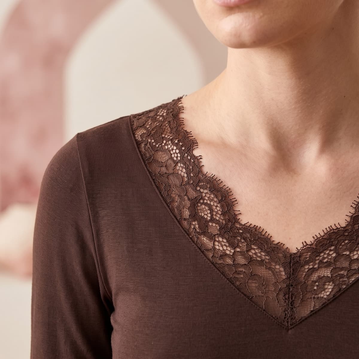 Dettaglio del pizzo mokka sullo scollo a V della maglia
